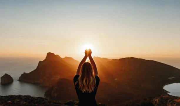 A figure standing on a hilltop at sunrise