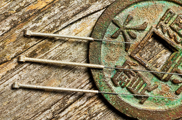 Acupuncture needles resting beside an antique Chinese coin