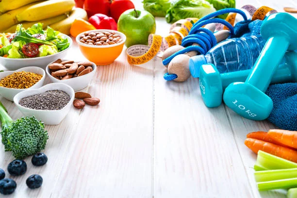Fresh vegetables, fruit, nuts and dumbbells laid out together