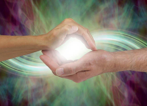 Two pairs of hands cupped around a glowing light