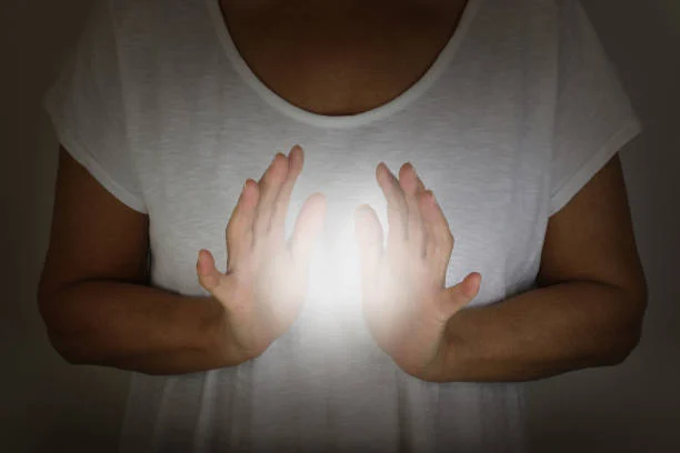Hands cupped around a ball of light against a dark background