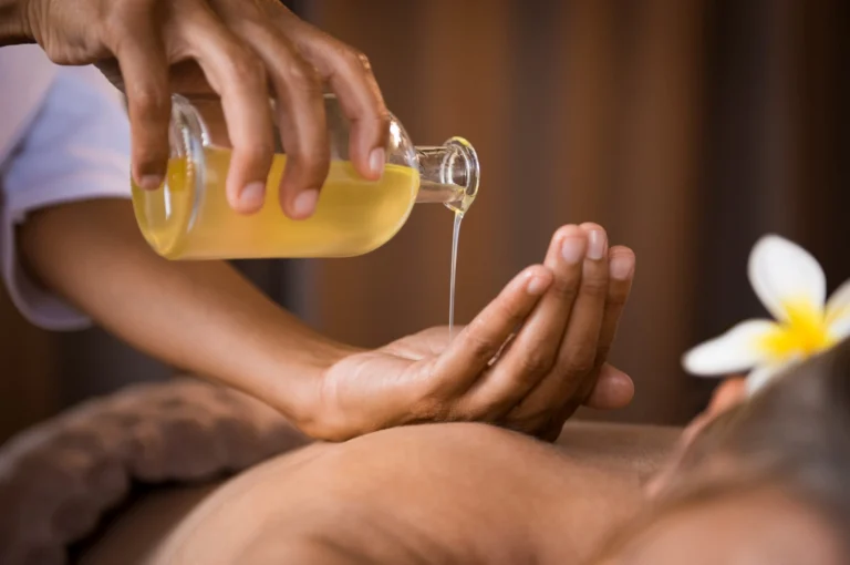 Registered massage therapist pouring massage oil during a treatment in Calgary