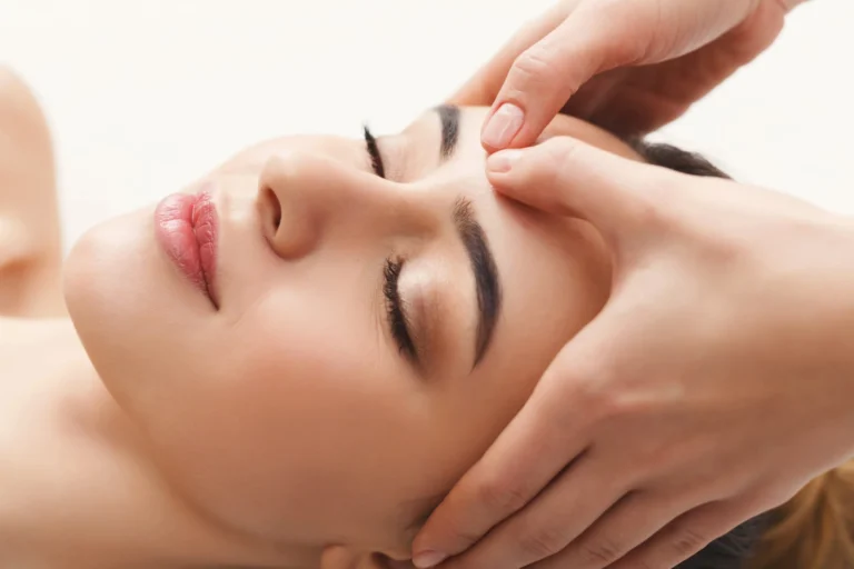 A massage therapist working along the jaw and cheekbones during a facial massage
